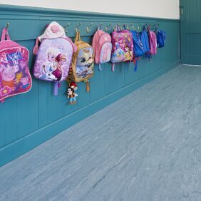 Blue colour homogeneous flooring in a school corridor with coat pegs 