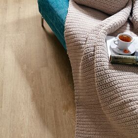 Close up of edge of sofa featuring light wood effect flooring in Cashmere Oak 