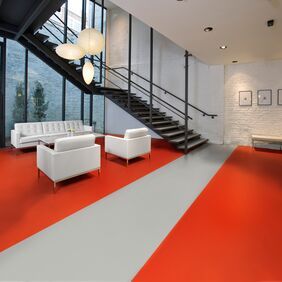 Large commercial waiting area with seating and red coloured flooring