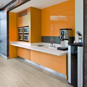 Light oak wood effect flooring in a refreshment area with orange walls 