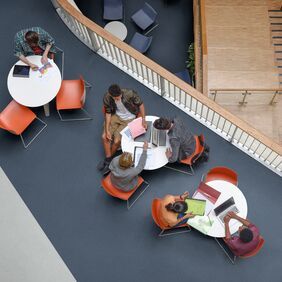 Dark blue safety flooring in a break out area with seating and tables
