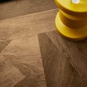 Upclose image of dark oak prism effect flooring and a yellow side table