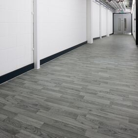 Silver grey oak wood effect flooring in a university corridor with white walls and grey door