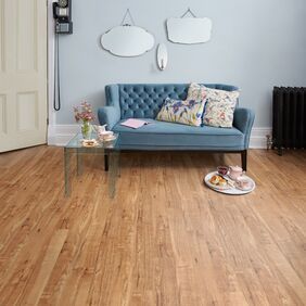 Light Blue soft velvet sofa with glass table tea and scones with Nut Tree oak colour flooring 