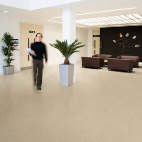 Cream colour stone effect flooring in a commercial corridor with a seating area 