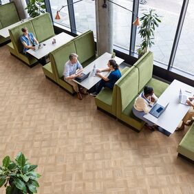 Basket weave patterned flooring in a communal area with booths being used for office space