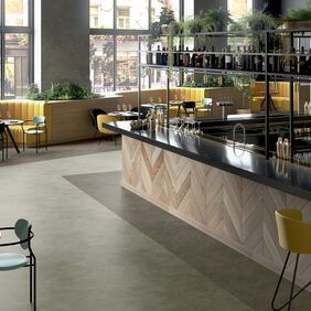 Light and dark stone effect flooring in a bar area with yellow seating 
