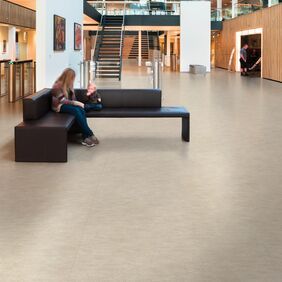 Light stone effect safety flooring in a large open space with seating 