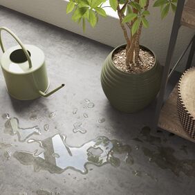 Upclose image of water spilled from a watering can onto grey flooring