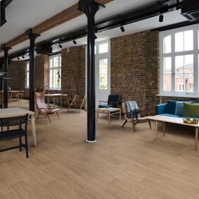 Warm oak effect flooring straight laid in a communal hang out room