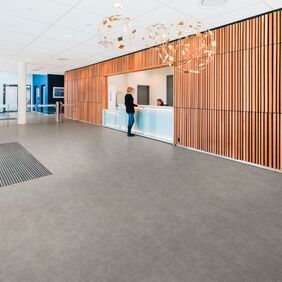 Grey stone effect saferty flooring in a large reception with wood paneling walls