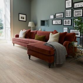 Deep red corner sofa, cushions, blanket, pictures, picture frames, wood floor