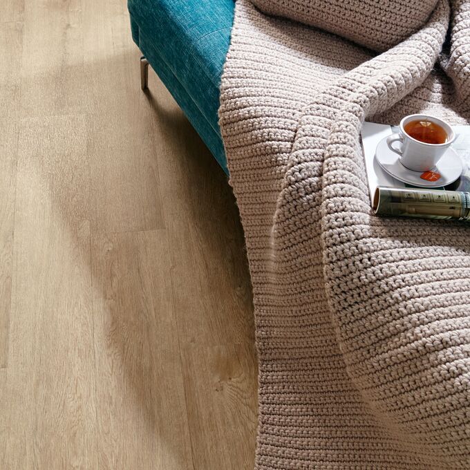 Close up of edge of sofa featuring light wood effect flooring in Cashmere Oak 