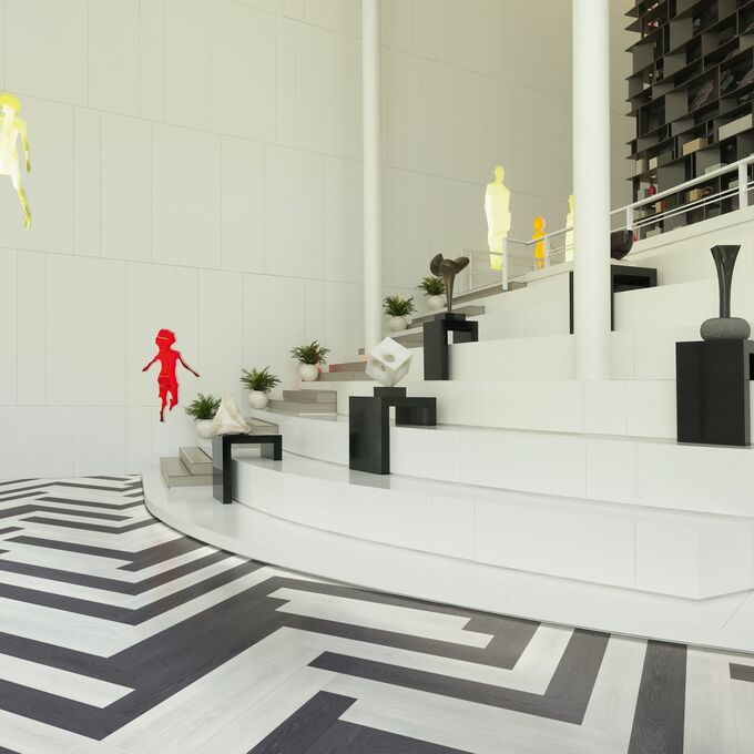 Black and white ash wood effect flooring laid in a herringbone design in a art gallery 