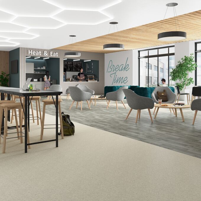 Light stone effect safety flooring alongside silver oak effect safety flooring in a communal break area in a education setting