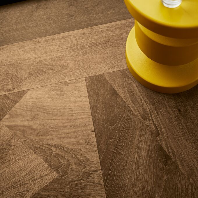 Upclose image of dark oak prism effect flooring and a yellow side table