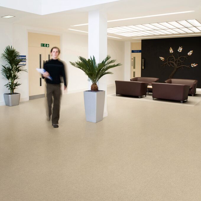 Cream colour stone effect flooring in a commercial corridor with a seating area 