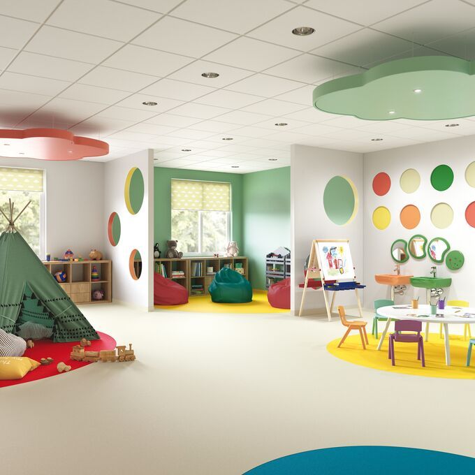 Neutral coloured safety flooring in a spacious nursery play area with bright walls and accessories