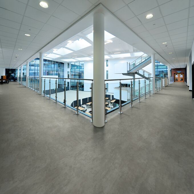 Dark concrete effect safety flooring in a large school corridor