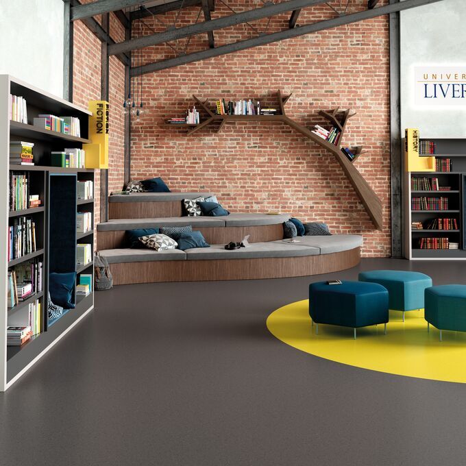 Modern library with dark coloured flooring and exposed brick walls