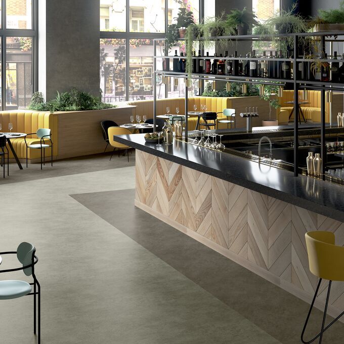 Light and dark stone effect flooring in a bar area with yellow seating 