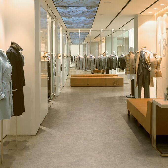 High end retail shop with cloths displayed on manneqin featuring a light stone effect flooring
