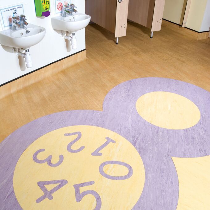 Light colour homogeneous flooring in a chidrens school toilet with a number motif design Incorporated