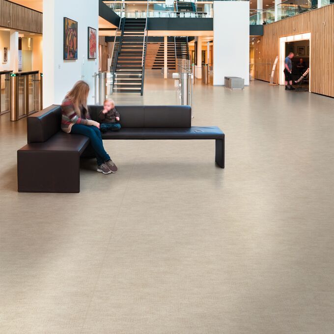 Light stone effect safety flooring in a large open space with seating 