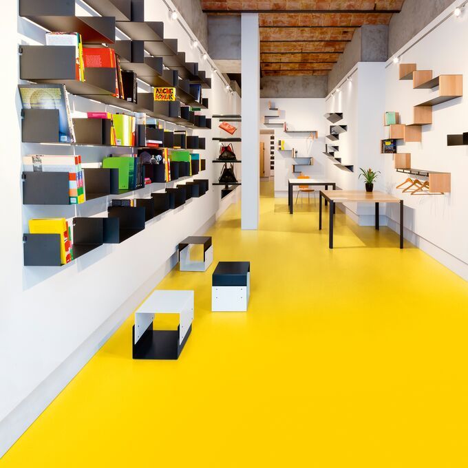 Room with yellow flooring and white walls with shelves